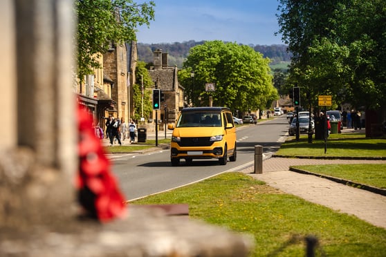 Yellow CamperKing campervan driving down high street