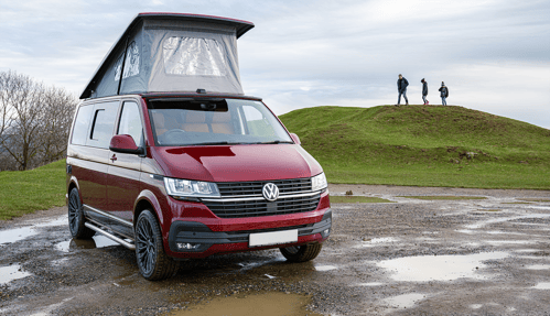 Red CamperKing campervan in park on rainy day