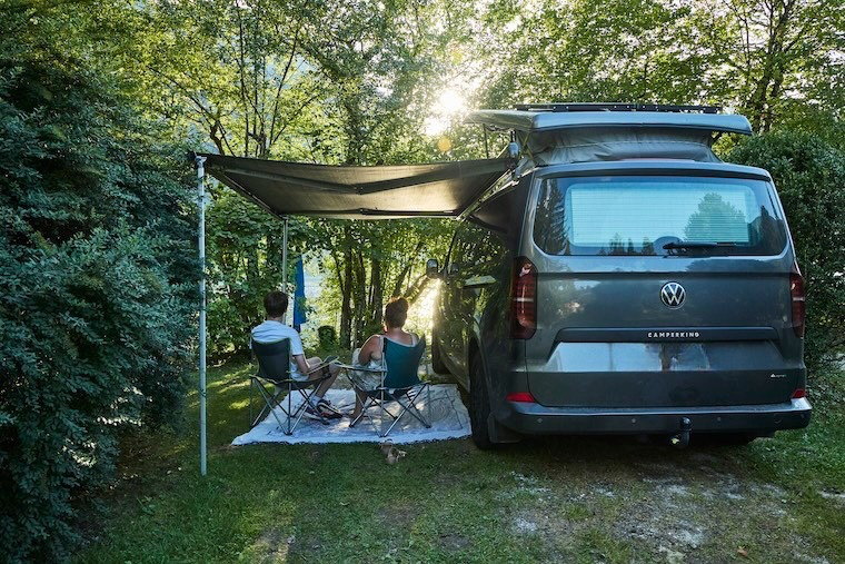 A family pitched up on campsite seated under their wind-out awning