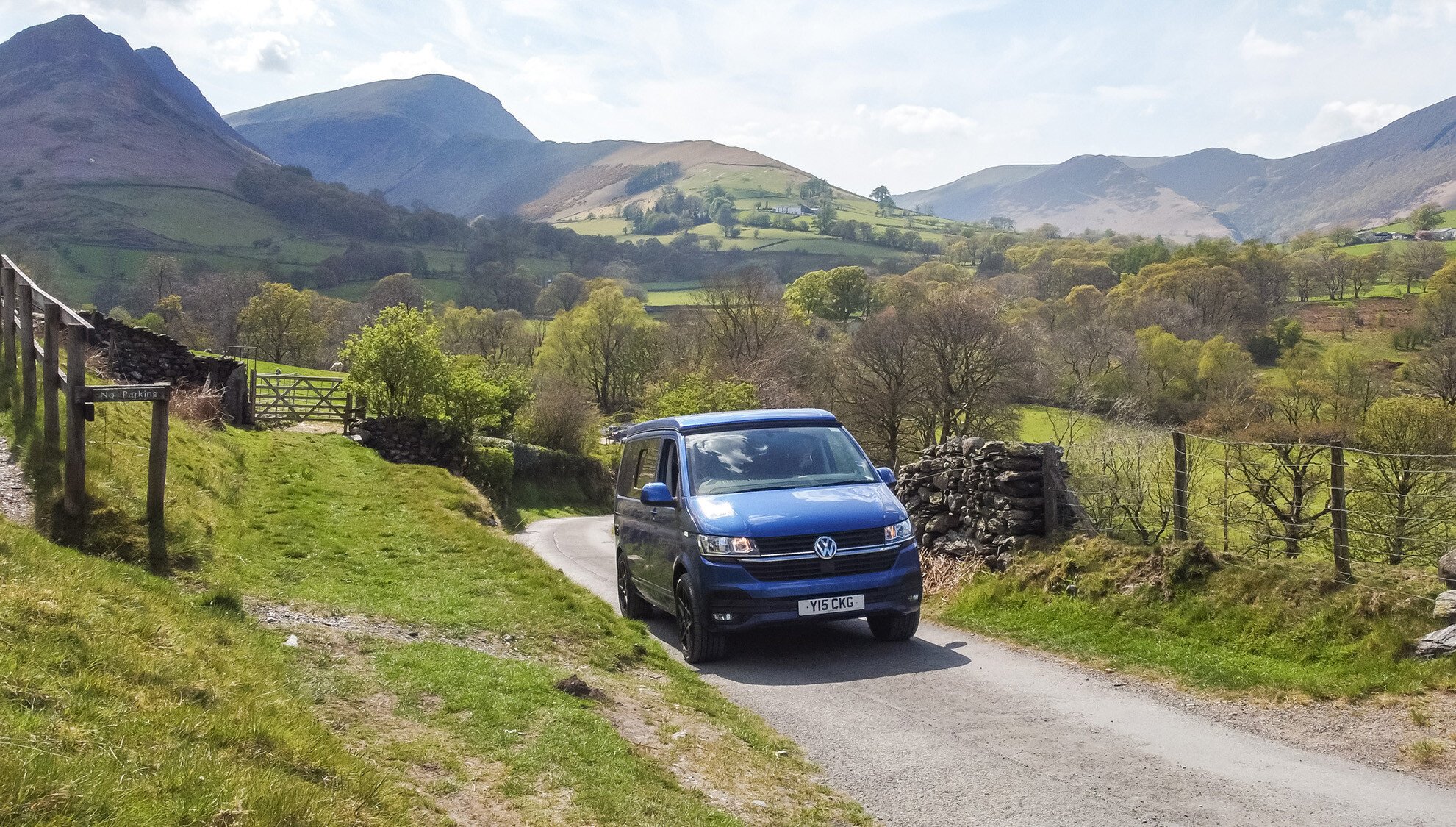 Campervan driving in the lake district with mountains in the background.