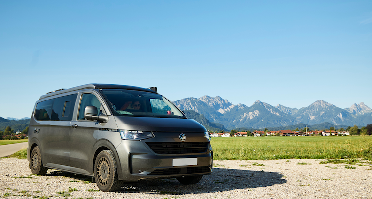 A grey VW T7 pictured with mountains in the background